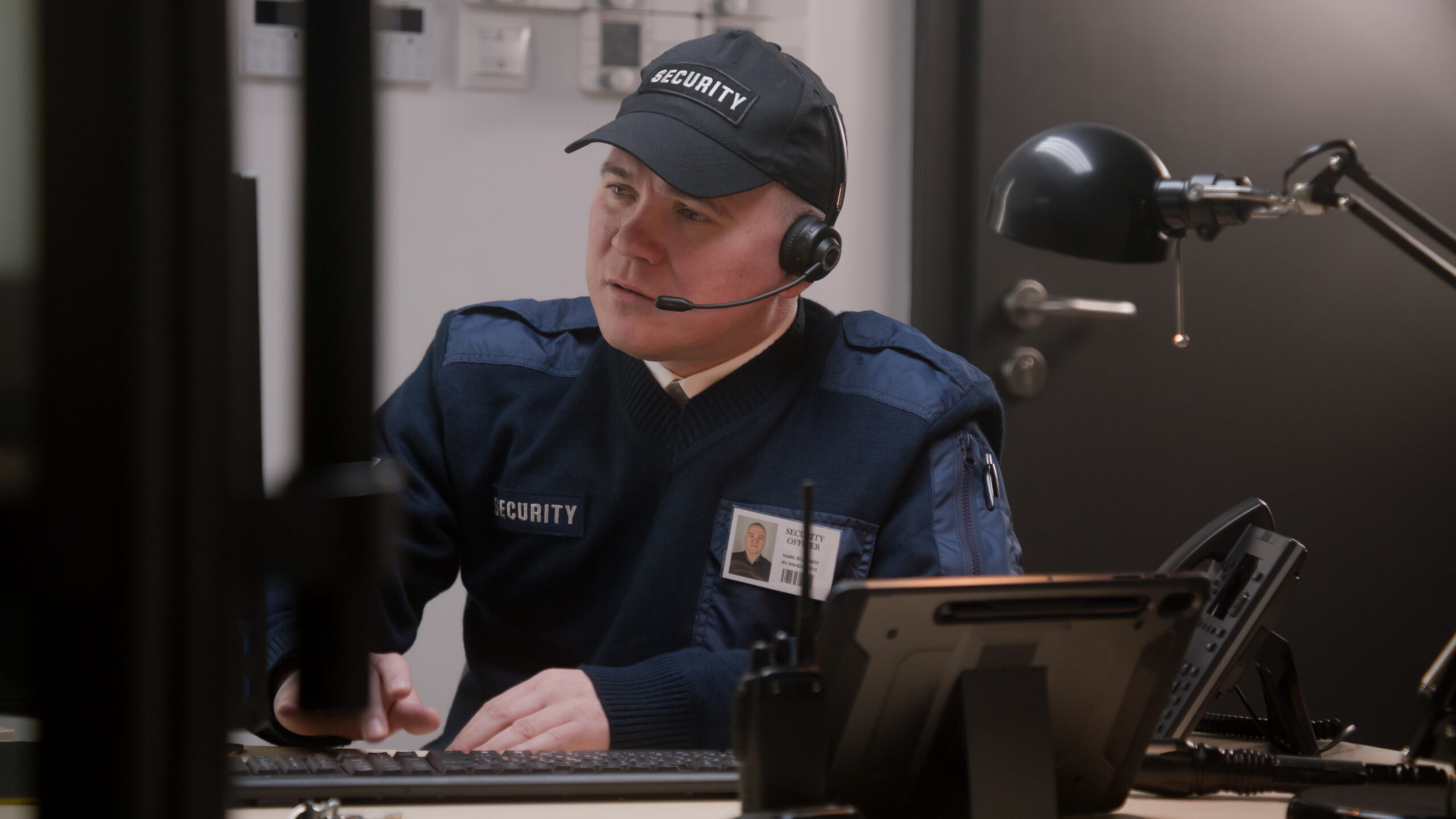 Security officer looks at monitor and talks by walkie talkie